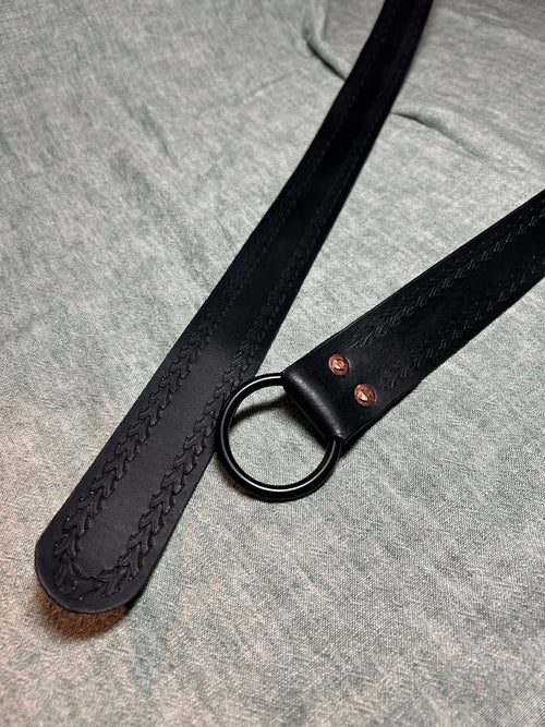 Black arrow edge-stamped leather ring belt, close-up of tip and pattern